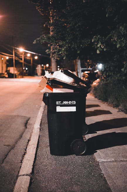A rectangular white metal sign mounted on a red brick wall, with black lettering that reads 'NO DUMPING OF RUBBISH.' The sign is positioned near the top left of the image, contrasting sharply with the